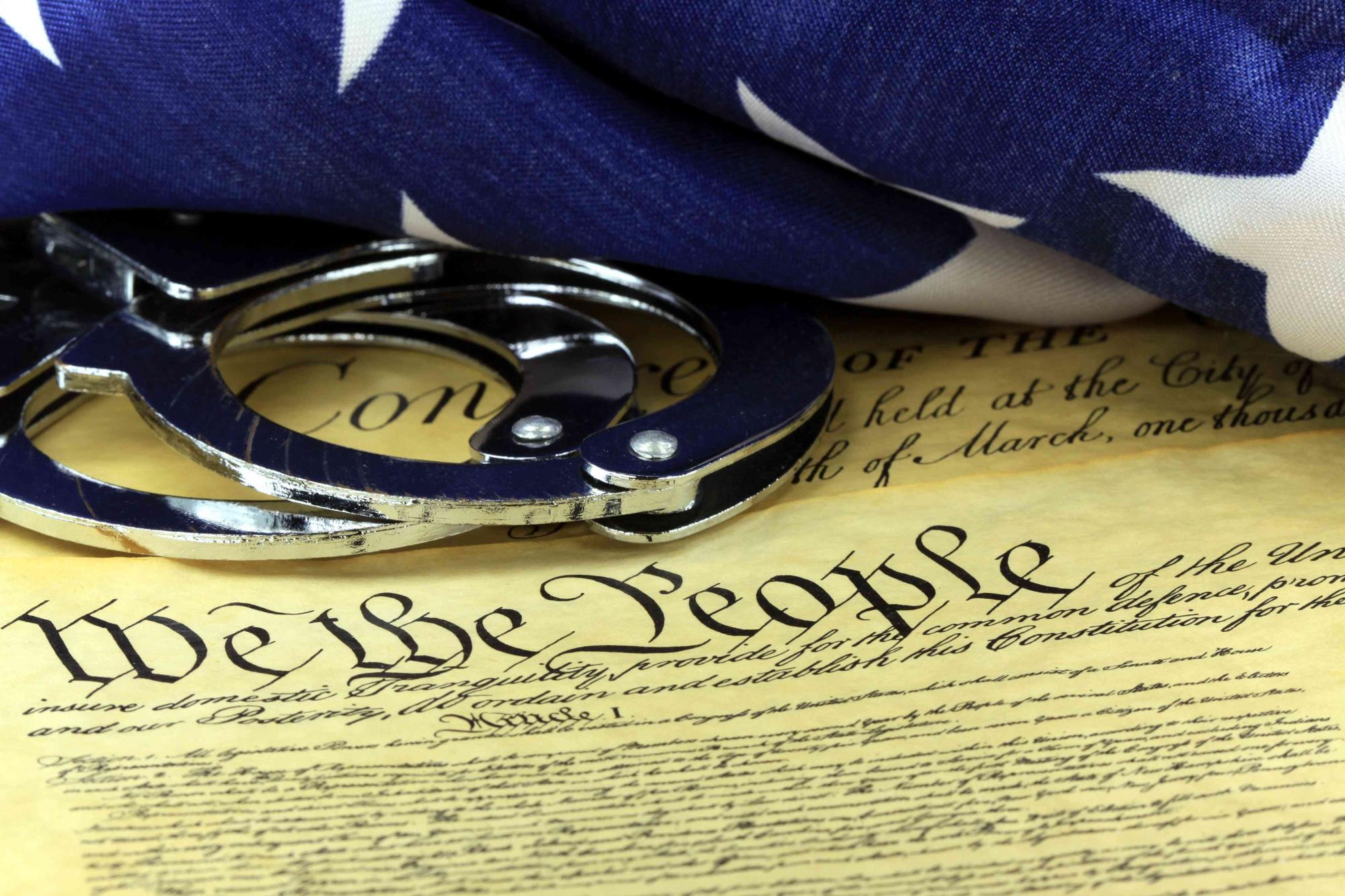 Handcuffs and flag on US Constitution - Fourth Amendment